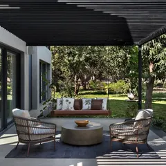 This comfortable outdoor seating area is nestled under a pergola, offering a tranquil spot to enjoy the surrounding mango orchard. The design prioritizes creating functional and inviting spaces that encourage time spent outdoors.
