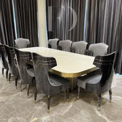 An opulent 10-seater dining set. The table features a lustrous white onyx top with a brass-trimmed base, surrounded by high-back chairs with unique cut-out details and dual-fabric upholstery.