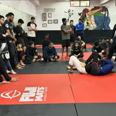 Students watch intently as a coach demonstrates a technique from the guard position. We create an environment where everyone is focused on learning and improving together.
