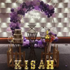 An elegant lavender and white themed decoration with a balloon arch, neon sign, and vintage-style props.