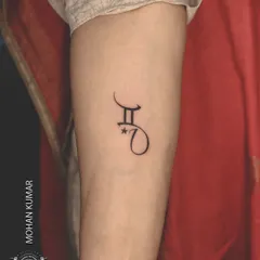 A minimalist tattoo combining the Gemini zodiac symbol with a client's initial. We can create custom symbols that merge different parts of your identity.