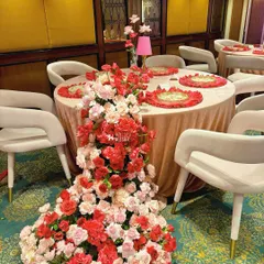 We use florals to create dramatic, flowing installations. Here, a cascade of red and pink roses flows from the tabletop to the floor, creating a stunning visual effect that is both opulent and artistic.
