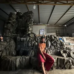 A moment of rest during the creation of a large, custom waterfall installation featuring a Buddha head. This project, combining sculpture and water elements, is a work in progress.