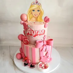 This two-tier Barbie cake was a dream to make for a young princess. It's decorated in shades of pink with stripes, bows, and of course, a beautiful Barbie topper for the perfect themed birthday.