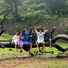 A fun group photo on a fallen tree log near Hidlumane Falls. The journey is filled with these playful moments.