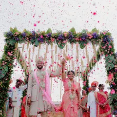 A moment of pure celebration as the happy couple is showered in flower petals under a stunning floral mandap. This is the kind of joyful, vibrant memory I love to capture, freezing the peak of happiness in time.