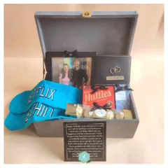 A perfect birthday hamper for a best friend, this gift includes fun "Netflix & Chill" socks, a personalized wallet, a photo frame with a favorite memory, and plenty of chocolates, all presented in a stylish grey suede box.