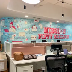 A concept-based wall mural for the Clovia office in Noida. This design, "Mission Fifty Million," uses fun typography and brand-related icons to create a motivational and visually engaging workspace.
