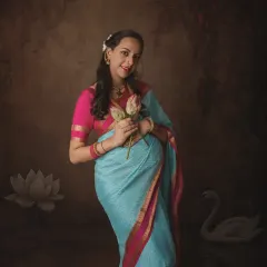 Holding lotus flowers, a symbol of purity and beauty, this mother-to-be in her elegant blue saree embodies grace in a fine art maternity portrait.