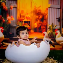 "Hatching" a plan for fun in our farmyard set. This setup features a large eggshell prop, hay, and a backdrop of a barn with chickens, creating a complete and playful rural scene.