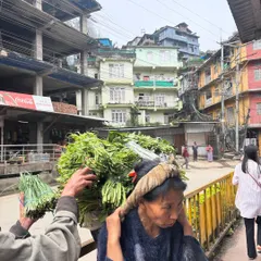 A woman at a market in Nagaland carrying a heavy basket of freshly harvested greens on her back. This is a common sight and a testament to the hard work of the local farmers who supply our ingredients.