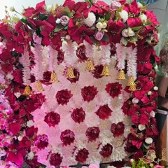 This intricate Navratri backdrop is made of red and pink flowers, with a lattice of hanging bells that adds a traditional and musical element. It's a rich and detailed design, perfect for welcoming the Goddess.