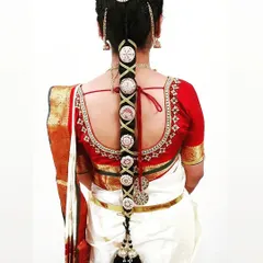 A classic Muhurtham braid on a bride wearing a traditional white and red Kanjeevaram saree. The hairstyle is adorned with beautiful silver and stone-work jada billalu for a complete bridal look.