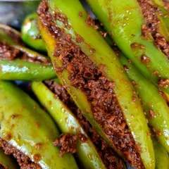 A close-up of the masala stuffing inside the green chilies. You can see the rich, coarse texture of the freshly ground spices. I make sure every chili is generously filled.