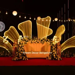 To show my range, here is a modern and glamorous stage I designed for an anniversary party. The custom-lit abstract shapes and elegant floral arrangements create a sophisticated and unforgettable nighttime ambiance.
