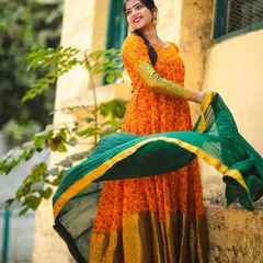The 'Naaranghi' series, featuring a vibrant orange Anarkali-style gown with a green dupatta. The flowing fabric and bright colors create a joyful and energetic look.