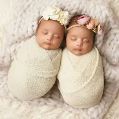 Swaddled side-by-side on a fluffy white blanket, these twin girls look like two perfect, tiny bundles. This is a classic and timeless twin newborn portrait.