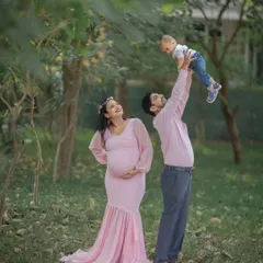 A park is a wonderful place for a family maternity shoot. Here, an older brother joyfully plays with his dad while mom watches on, creating a perfect candid family moment.