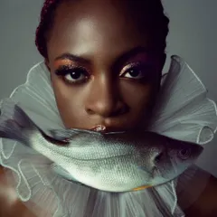 A surreal beauty portrait exploring the relationship between humanity and nature. The unexpected element of the fish against the classic ruffle collar is meant to be jarring and beautiful, challenging conventional standards.