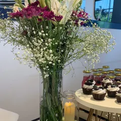 Another view of the fresh floral centerpiece, showing how it complements the dessert table. The details, like the candle and cupcakes, are all part of the overall event design.