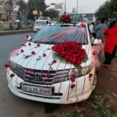This Honda City is decorated with a large bouquet of fresh red roses on the bonnet, with single roses taped across the car. This is a classic and affordable wedding car decoration style.