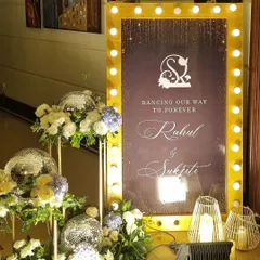 A glamorous welcome to a Sangeet night. We used a marquee-style sign with bulb lights, disco balls, and floral arrangements to set a "Black, White, and Gold" theme, promising a night of shimmer and dance.