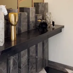 This dramatic console table, crafted from stacked blocks of grey marble, makes a powerful statement in the entryway. The quirky decor adds a touch of personality and fun.