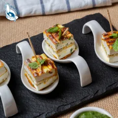 A closer look at our Rozali Stuffed Paneer Sandwiches. Served on elegant tasting spoons with a mint garnish, they are a beautiful and delicious addition to any appetizer menu.