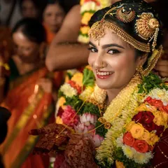 A stunning portrait of a South Indian bride, adorned with traditional jewelry and flower garlands, smiling directly at the camera. We capture the beauty and grace of our brides.
