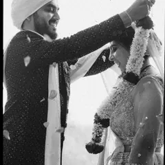 The Varmala ceremony, captured in timeless black and white. The falling petals and the couple's smiles create a dynamic, emotional image of this key wedding moment.