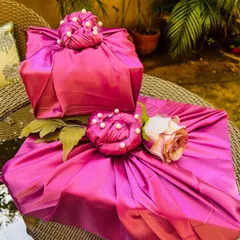 My luxury trousseau packing service transforms your gifts into works of art. Here, presents are wrapped in regal magenta satin fabric, finished with intricate pearl detailing and a delicate rose accent, ensuring the presentation is as memorable as the gift inside.