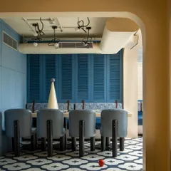 A view into the blue dining zone at Masala, framed by a soft, arched doorway. The custom floor tiles and unique chair design demonstrate our focus on creating a cohesive and memorable spatial identity through bespoke details.