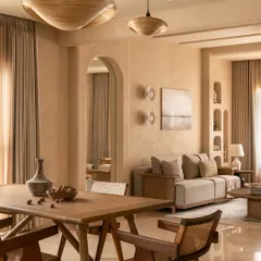 The dining area is defined by handcrafted wood veneer pendants and Pierre Jeanneret-inspired cane chairs. These elements bring together mid-century design wisdom and a timeless, organic aesthetic for intimate gatherings.