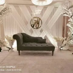 For a sophisticated engagement, we designed this all-white theme with crisscross draping, cherry blossom trees, and a custom neon sign. The elegant chaise lounge completes this clean, modern look for a banquet hall.