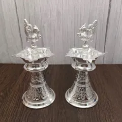 A pair of German silver Nakashi deepas, featuring detailed floral carvings. These stand diyas are perfect for placing on either side of your temple, creating a balanced and divine ambiance.