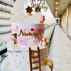 A dreamy two-tier twinkle twinkle little star themed cake. This design features a quilted bottom tier and a pink watercolor top tier with a fondant moon, clouds, and a ladder, perfect for a baby's first birthday.
