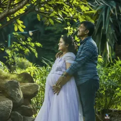 A candid moment of a couple looking towards their future together, framed by lush greenery. I use natural light to create soft, romantic outdoor maternity portraits.