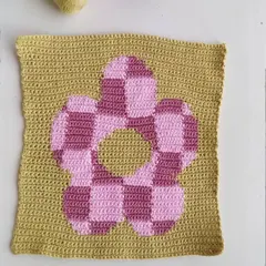 This checkered flower square is an example of tapestry crochet. This technique allows for creating detailed, graphic images with yarn, perfect for wall hangings or pillows.