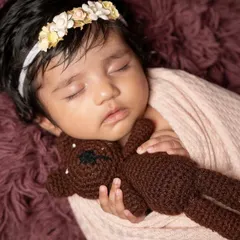 There is nothing more precious than a newborn's peaceful sleep. This close-up shot focuses on the delicate features and the comfort of a tiny teddy bear, creating a tender memory of those first few weeks.