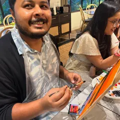 The look of pure enjoyment! A participant wearing a protective apron, fully immersed in his painting during a weekend workshop.