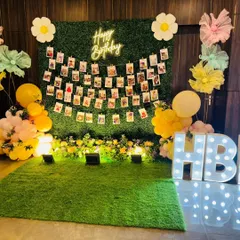 A photo memory wall using an artificial hedge panel as the base. I strung rows of photos for guests to enjoy, and framed the display with balloons, a neon sign, and marquee letters.
