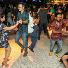 A line of dancers practicing their footwork together during a studio social. It's a great, supportive environment to build confidence and muscle memory.