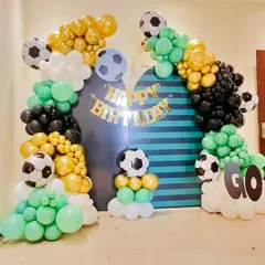 For the ultimate football fan, we transformed this space into a mini stadium. This football-themed birthday decoration includes balloon arches in green, black, white, and chrome gold, along with multiple football-themed foil balloons. A custom striped backdrop and a "GO" cutout add to the sporty atmosphere.