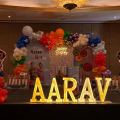 The main stage for Aarav's party, featuring a colorful balloon arch, a "Happy Birthday" neon sign, and all the favorite Cocomelon characters.