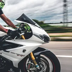 A close-up panning shot focusing on the front half of the Triumph Daytona. This angle emphasizes the bike's design and the rider's focused posture.