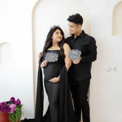 Boy or Girl? This creative gender reveal photo captures the couple's excitement and curiosity with fun props, all while looking stunning in matching black outfits.