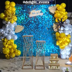 This vibrant and modern birthday backdrop features a brilliant blue shimmer wall that catches the light beautifully. We've framed it with organic balloon columns in yellow, silver, and white, adding a neon sign and starburst accents for a fun, high-energy party atmosphere.