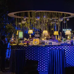 A quirky and stylish circular bar with a polka-dot front, adorned with hanging disco balls and classic table lamps for a unique party vibe.