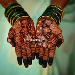 A beautiful, dark stain on a traditional lotus design. The contrast with the green bangles makes the rich color of the henna pop.