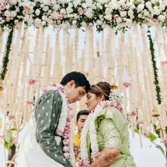 A beautiful, intimate moment of a couple under a canopy of hanging tuberoses and pink flowers. This design focuses on creating a delicate and romantic atmosphere for the ceremony.